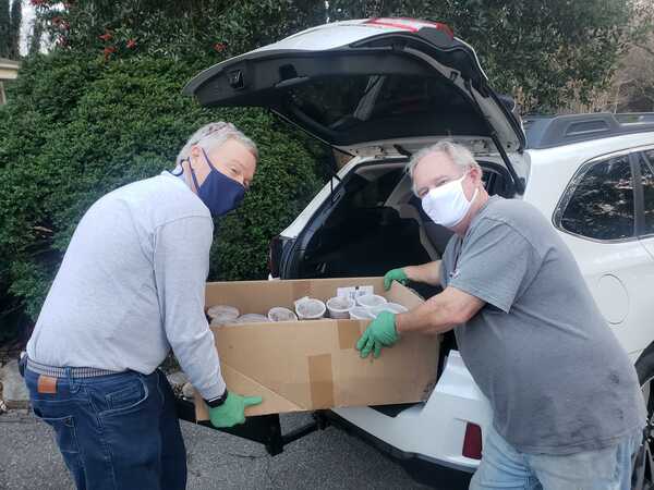 Older men wearing face masks holding box